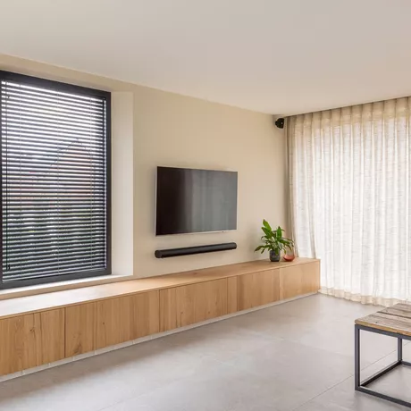 Combinatie van zwarte lamellen en schuifgordijnen in een woonkamer geplaatst door Altex Raamdecoratie